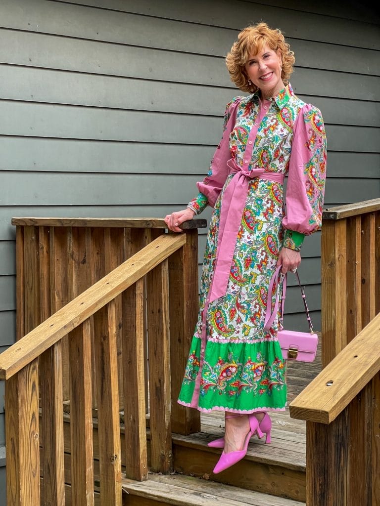 woman over 50 standing on stairs outdoors wearing colorful boden shirtdress print