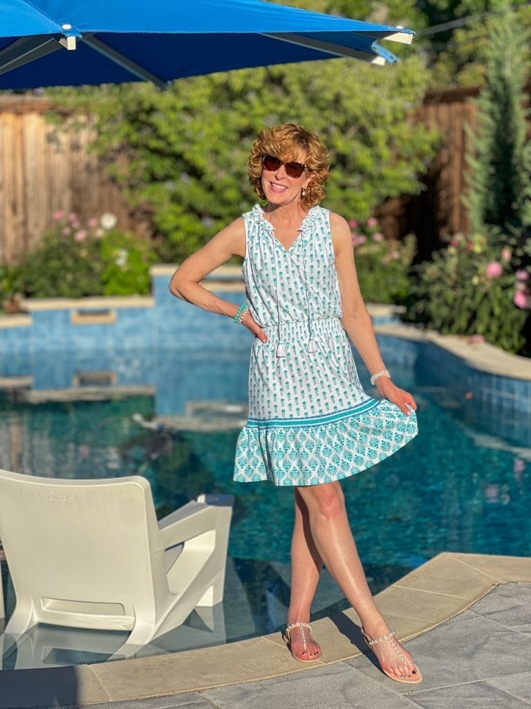 woman wearing sun protective clothing standing next to pool in cabana life summer dress in amalfi print