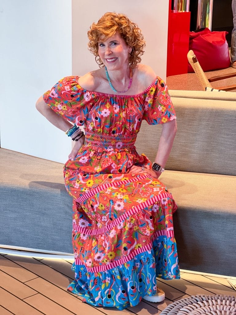 woman sitting on a fabric bench wearing printfresh off the shoulder dress and colorful jewelry