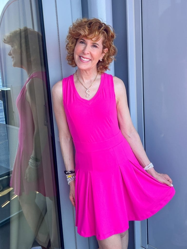 woman standing on balcony of a cruise ship wearing a hot pink athleisure dress