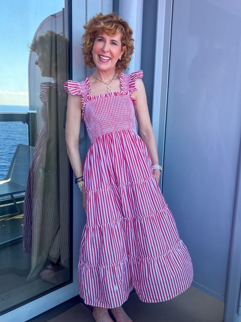 woman standing on balcony of a cruise ship wearing hill house home red and white striped ellie nap dress