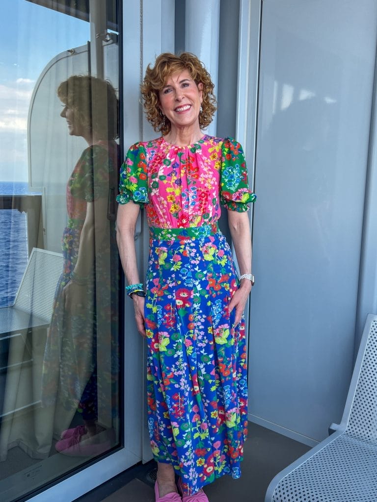 woman standing on balcony of a cruise ship wearing boden colorful maxi dress