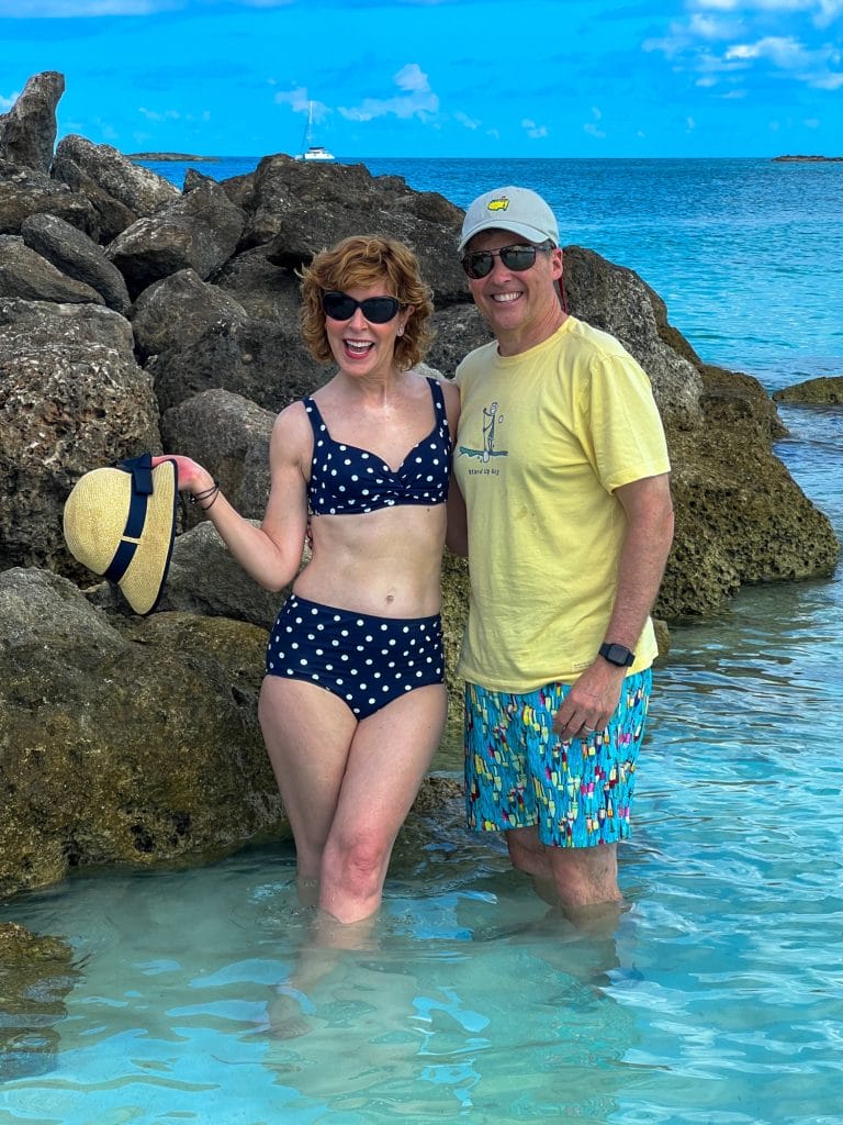woman standing in the water near rocks wearing polka dot bikini with husband