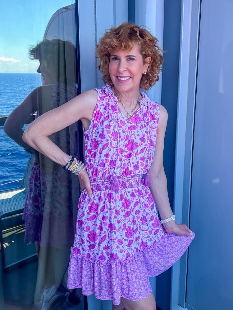 woman posing on a cruise ship balcony wearing sun protective clothing