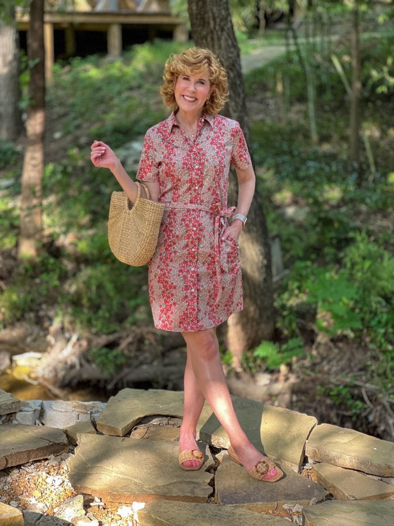 woman standing in the woods wearing a floral shirtdress