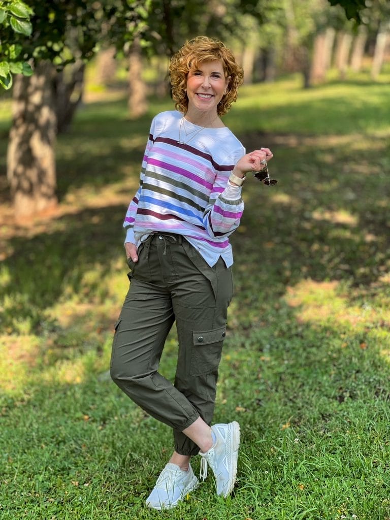 woman standing in the woods wearing a transitional outfit