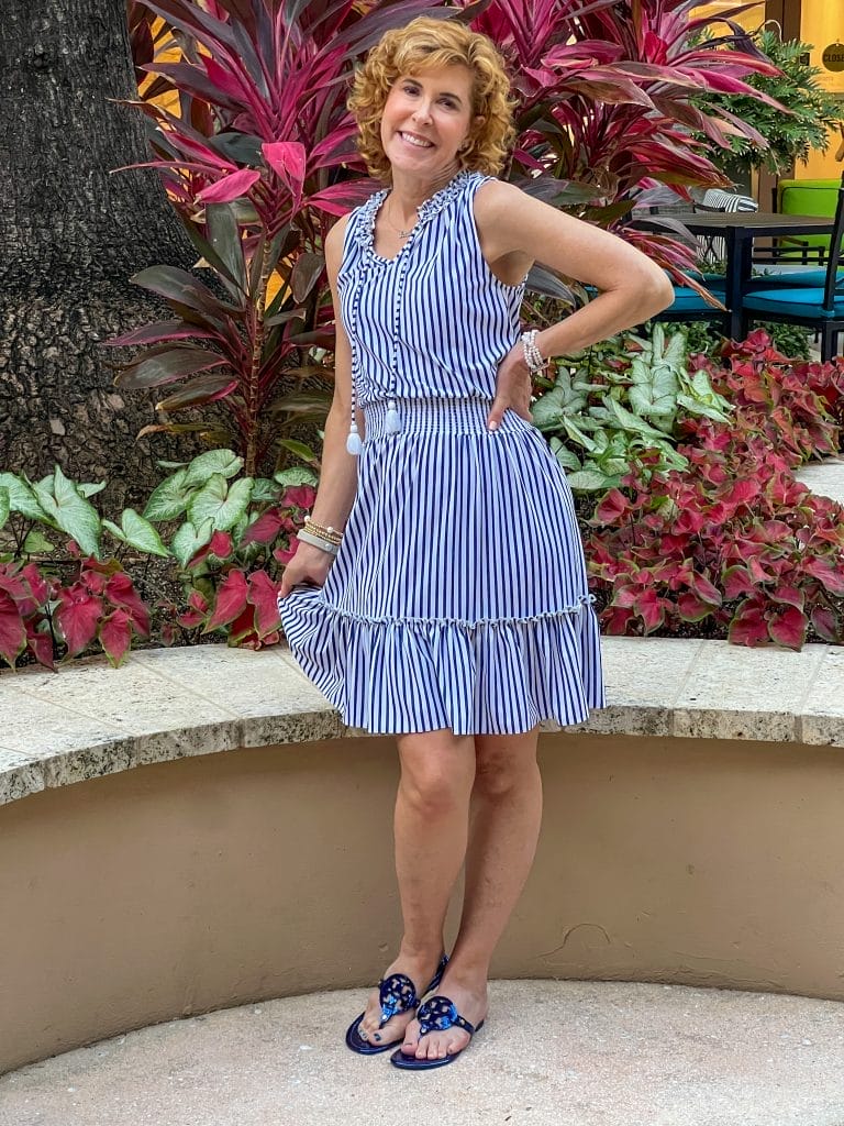 woman wearing cabana life navy Stripe Sleeveless Ruffle Dress and blue tory burch sandlas standing in front of tropical vegetation at baha mar