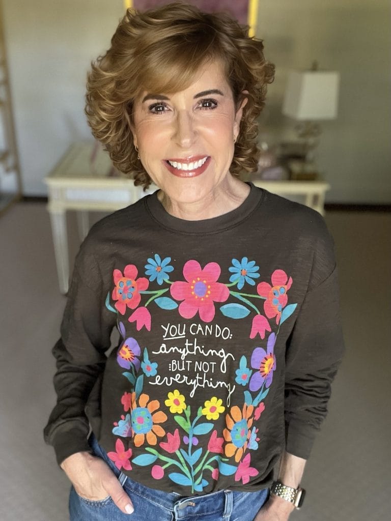 Woman standing inside with a floral tee from natural life on