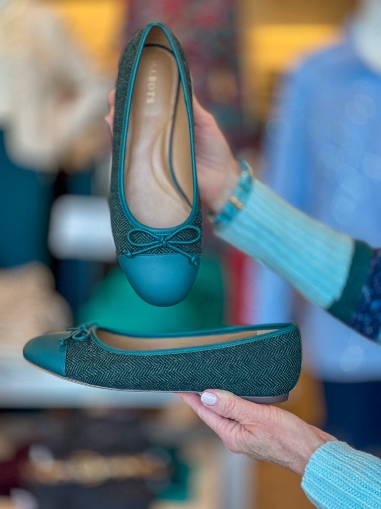 woman's hands holding a pair of talbots teal tweed ballet flats showing the fall trends for 2024