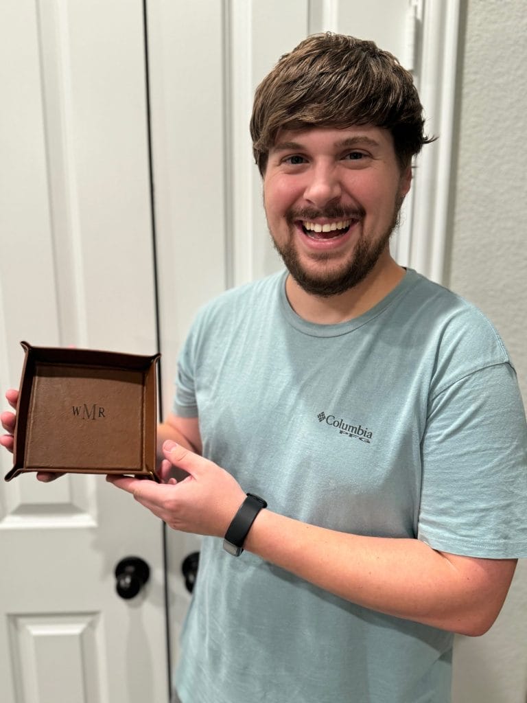 guy holding leather valet tray dressed in green tee shirt