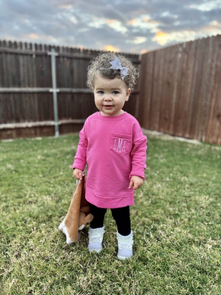 baby standing in yard wearing pink pullover from marleylilly