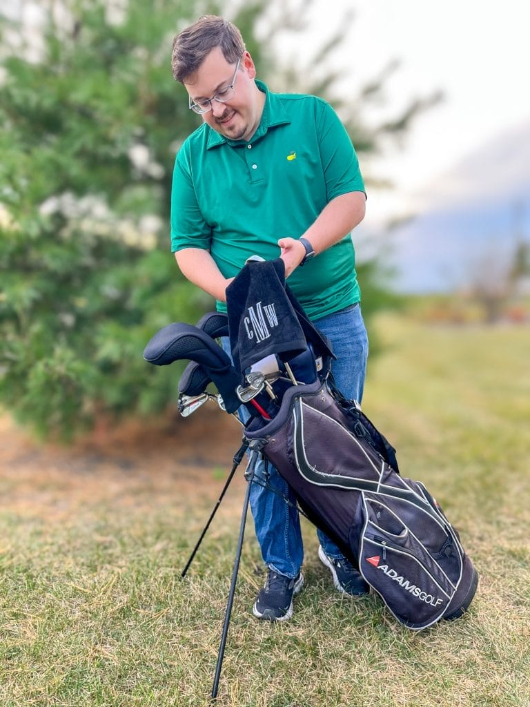 golfer in green shirt looking at his golf bag and golf towel from marleylilly