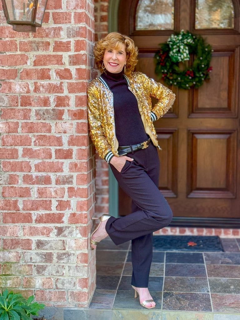 woman leaning on a brick post wearing sequin jacket for nye