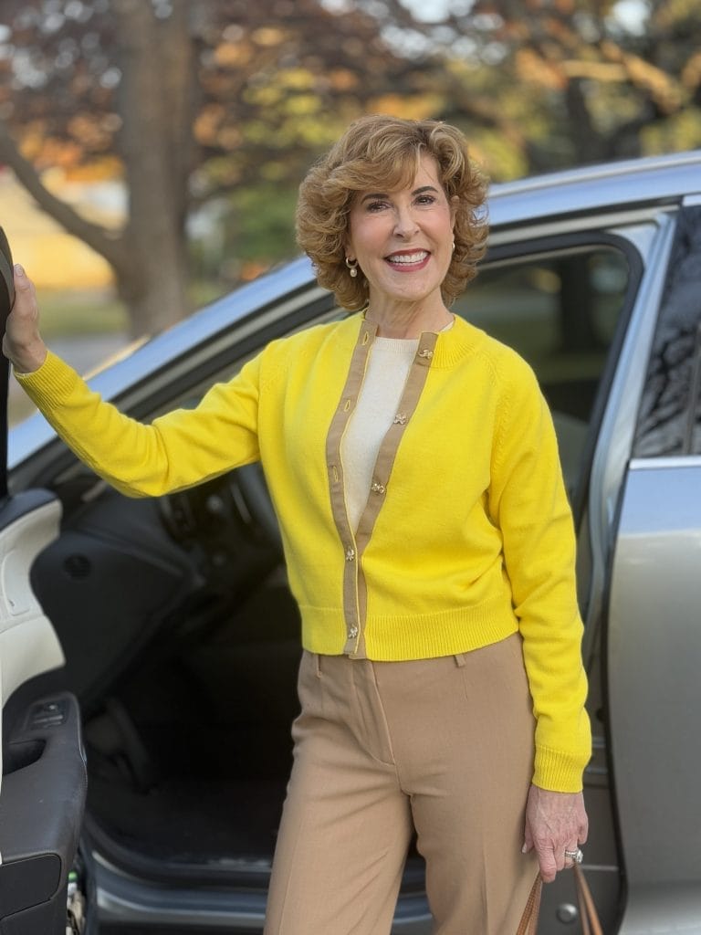 woman standing near car wearing yellow Lucia sweater from Avara and khaki pants